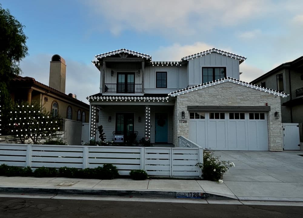 Modern two-story house decorated with white lights, featuring a stone exterior and garage.