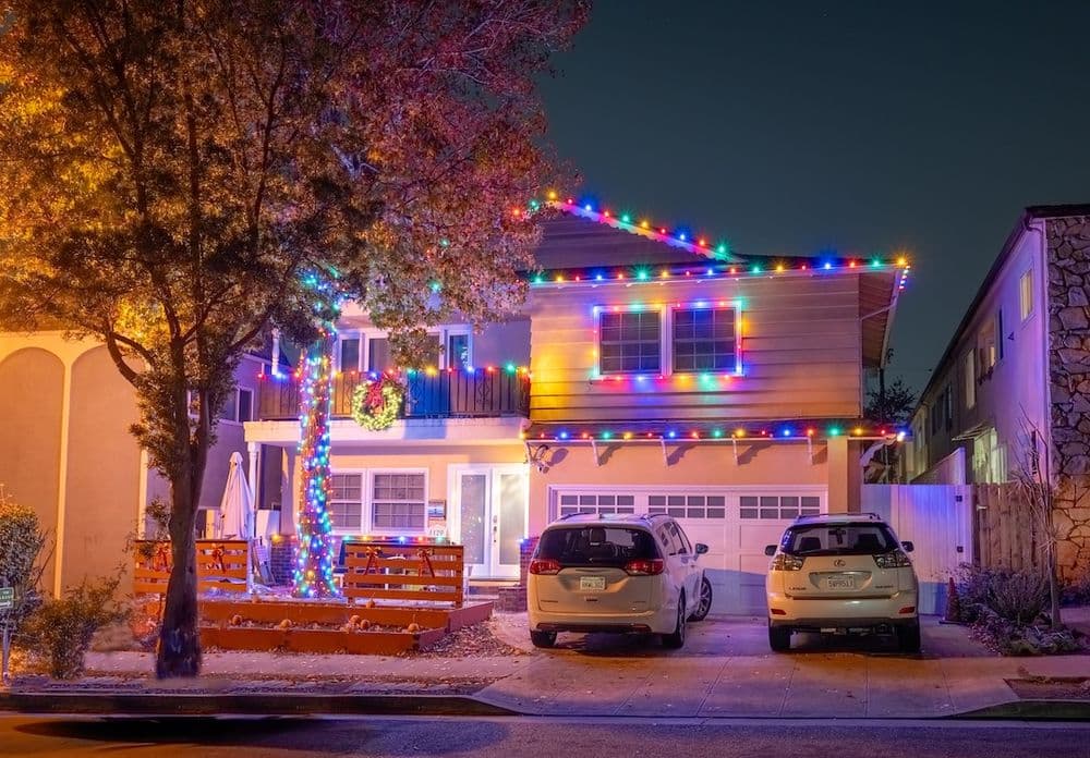 House adorned with colorful Christmas lights at night, showcasing festive holiday spirit.