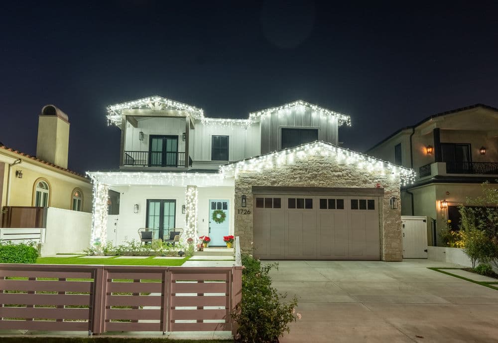 Modern house with decorative lights at night, showcasing a welcoming front yard and garage.